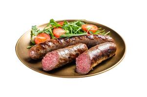 Roasted meat sausages with arugula and tomato salad. Isolated on white background. Top view. photo