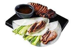Traditional served Peking Duck with cucumber, green onion, in wheaten chinese pancakes. Isolated on white background. Top view. photo