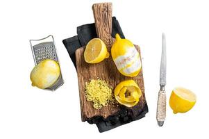 Grated Lemon Zest and spiral peel on wooden board. Isolated on white background, top view. photo
