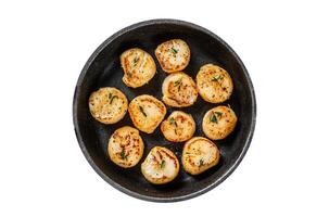 Fried scallops with butter sauce in a pan. Isolated, white background. Top view. photo