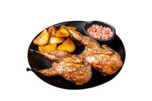 Roast whole quails in a plate with fried potato. Isolated on white background. photo
