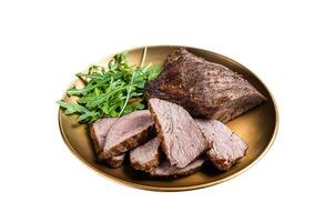 Roast Tri Tip or sirloin bottom beef steak on a plate with arugula. Isolated on white background. Top view. photo