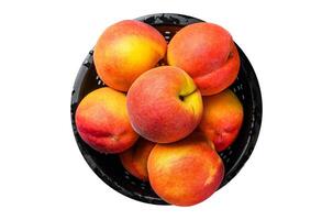 Peaches fruit in a black colander on the table. Isolated, white background. photo