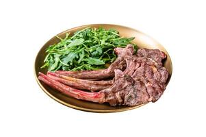 BBQ grilled lamb cutlet or mutton chop steak with arugula salad on a plate. Isolated on white background. Top view. photo