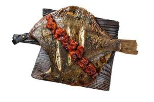 Grilled Flounder or plaice with tomato sauce on wooden cutting board. Isolated on white background. photo