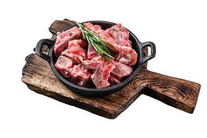 Raw diced meat cubes with bone in a pan. Isolated, white background. photo