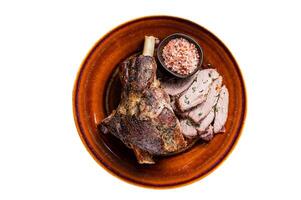 BBQ Roast Lamb mutton leg sliced on a rustic plate. Isolated on white background photo