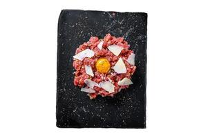 Tartar beef with a quail egg, capers and Parmesan cheese. Isolated on white background, Top view. photo