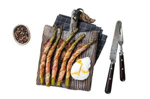 Roasted green asparagus wrapped in a bacon with egg. Isolated on white background, top view. photo