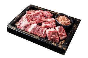 Uncooked Raw diced cubes of lamb meat in wooden tray with salt and thyme. Isolated on white background. Top view. photo