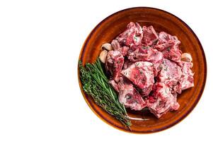 Raw mutton meat diced for goulash or stew with bone on a rustic plate. High quality Isolate, white background. photo
