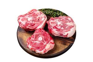 Raw lamb neck chops, fresh mutton meat on a butcher board with herbs. Isolated on white background. Top view. photo