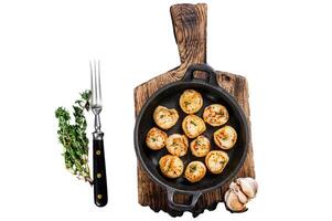 Fried scallops with butter sauce in a pan. Isolated on white background, top view. photo