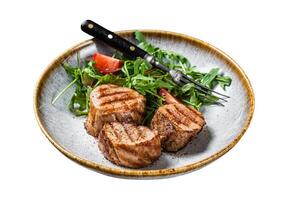 Grilled pork medallions steaks, tenderloin fillet with salad in plate. Isolated on white background. photo