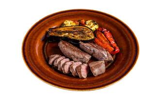 Grilled mutton tenderloin Fillet Meat, lamb sirloin on rustic plate with vegetables. Isolated on white background photo