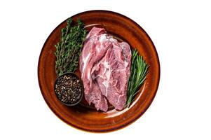 Raw piece of pork shoulder meat with spices on a rustic plate. High quality Isolate, white background. photo