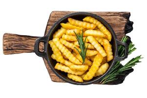 Fried Crinkle French fries potatoes in a pan. Isolated on white background, top view. photo