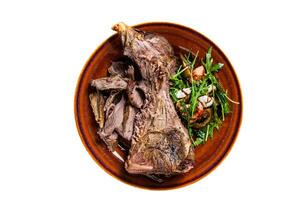 Grilled goat or lamb mutton shoulder meat in a rustic plate with salad. Isolated on white background. photo