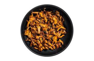 Fried chanterelle mushrooms with onions and thyme in a skillet. Isolated, white background. Top view. photo