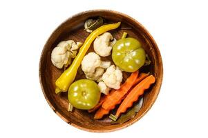 Salted and pickles vegetables preserve in a wooden plate. Isolated, white background. Top view. photo