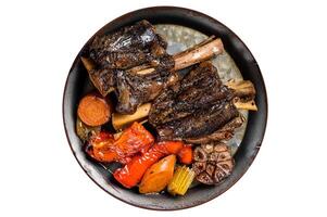 Homemade Braised Lamb Shanks with Sauce and Herbs in a steel tray. Isolated on white background. photo