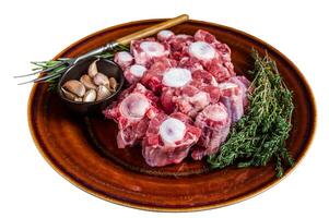 Fresh uncooked beef Oxtail cut Meat on rustic plate with herbs. Isolated on white background. photo