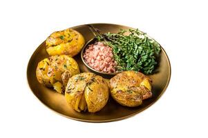 Crushed, smashed potatoes baked with rosemary and thyme on plate. Isolated on white background. Top view. photo