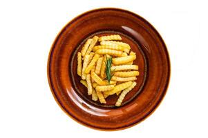 Fried Crinkle French fries potatoes or chips in a rustic plate. Isolated on white background. photo