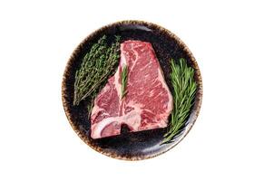 Dry aged Raw porterhouse beef meat Steak, fresh T bone on rustic plate with spices. Isolated on white background. photo