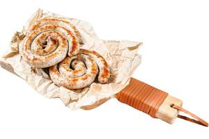 Grilled sausages spiral served on cutting board. Isolated on white background. Top view. photo