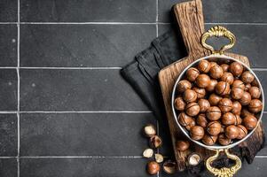 Macadamia nuts in a shell ready to eat. Black background. Top view. Copy space photo
