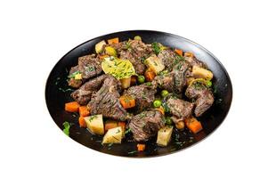 Beef meat stew, braised beef meat with vegetables in a plate. Isolated on white background. photo