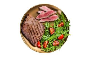Roasted Flank or Flap Steak in a plate with salad. Isolated on white background. photo