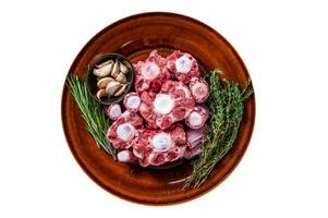 Fresh uncooked beef Oxtail cut Meat on rustic plate with herbs. Isolated, white background. Top view. photo