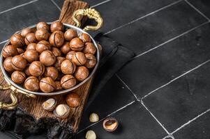 Macadamia nuts in a shell ready to eat. Black background. Top view. Copy space photo