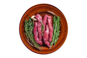 Uncooked Raw lamb tenderloin Fillet Meat in rustic plate with thyme and rosemary. High quality Isolate, white background. photo
