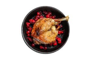 Fried duck leg with cranberrie sauce in a pan. Isolated, white background. Top view. photo