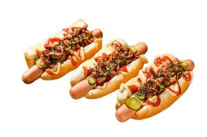 caliente perros completamente cargado con frito tocino, cebolla y en escabeche pepinos aislado en blanco antecedentes. foto