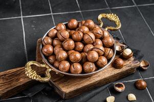 Macadamia nuts in a shell ready to eat. Black background. Top view photo