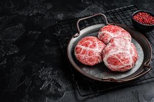 Raw pork cutlet, Crepinette with spices and herbs. Black background. Top view. Copy space photo
