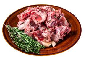 Raw mutton meat diced for goulash or stew with bone on a rustic plate. High quality Isolate, white background. photo