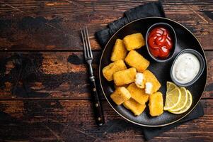 Fried Fish Sticks Fingers with sauce in a plate. Wooden background. Top view. Copy space photo