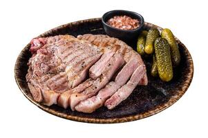 Grilled meat - Pork steaks from neck fillet meat in plate with pickled cucumbers. Isolated on white background. Top view. photo