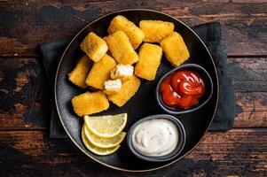 Fried Fish Sticks Fingers with sauce in a plate. Wooden background. Top view photo
