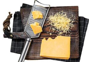 Grated cheddar cheese piece on a wooden board. Isolated on white background, top view. photo
