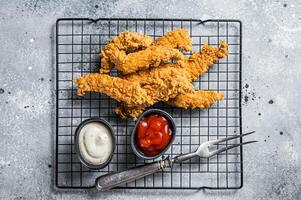 Dip fried Chicken Steak Fingers strips with sauces. Gray background. Top view photo