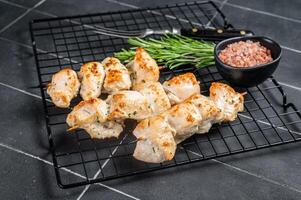 Chicken shish kebab, grilled skewers with herbs and spices on a rack. Black background. Top view photo