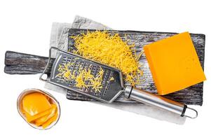 Grated Cheddar Cheese on a wooden cutting board. Isolated on white background, top view. photo