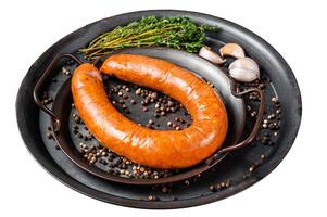 Smoked sausage with thyme and spices in a steel tray. Isolated on white background. Top view. photo