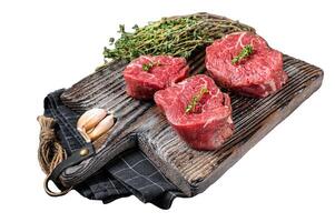 Prime raw Fillet mignon steaks on a wooden board with thyme and garlic. Isolated on white background, top view. photo